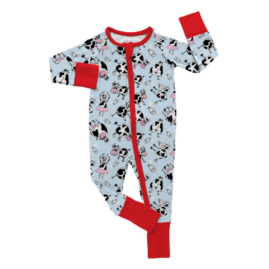 Children's pajamas with a cow and ballerina character print, predominantly blue with red trim, a full-body suit with a zipper down the front.
