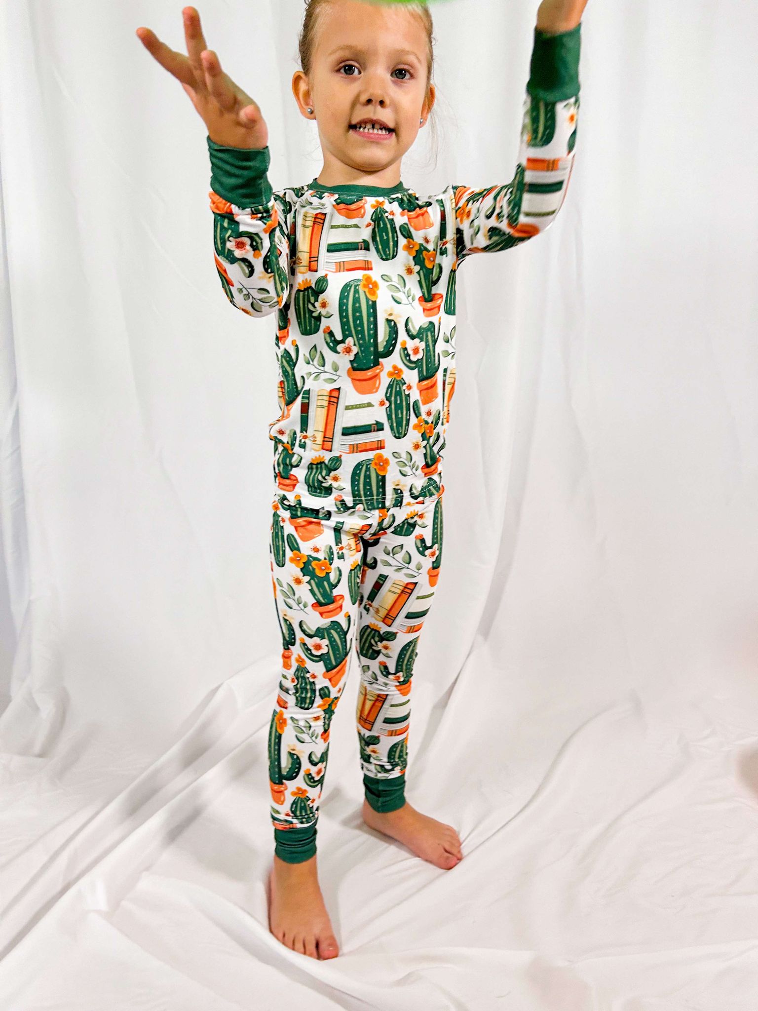 a young girl wearing storytime in the desert bamboo long sleeved pajama set while holding her hands up to play with a balloon