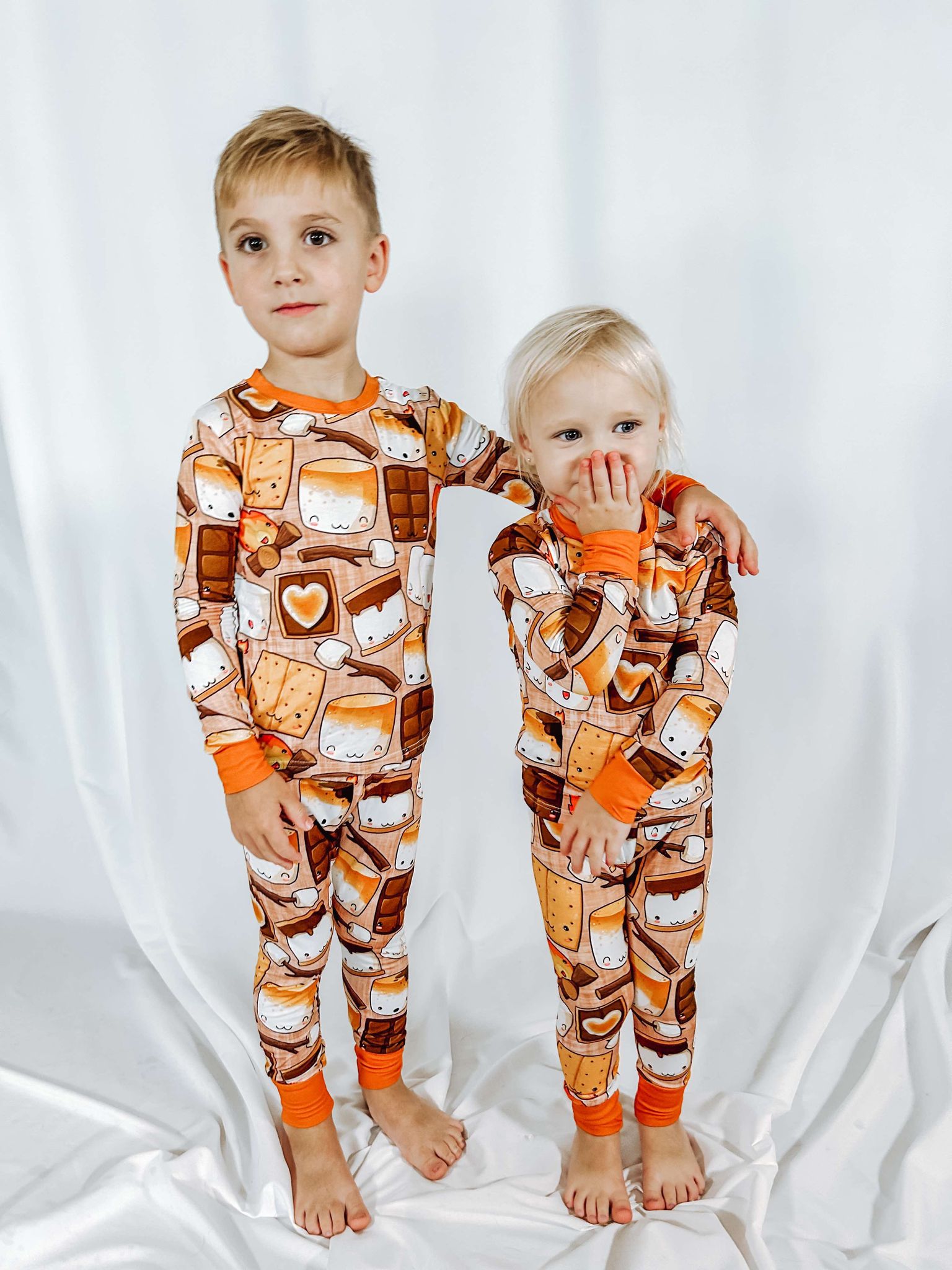 a brother and a sister with matching bamboo pajamas featuring smores  and a campfire
