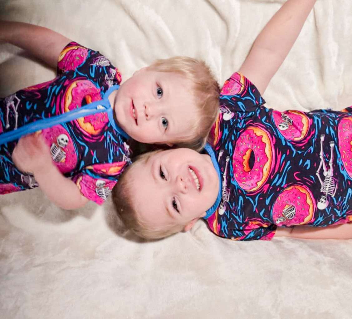 two boys laying head to head both wearing ghoulish glaze bamboo pajamas one in two piece set and one in zippy