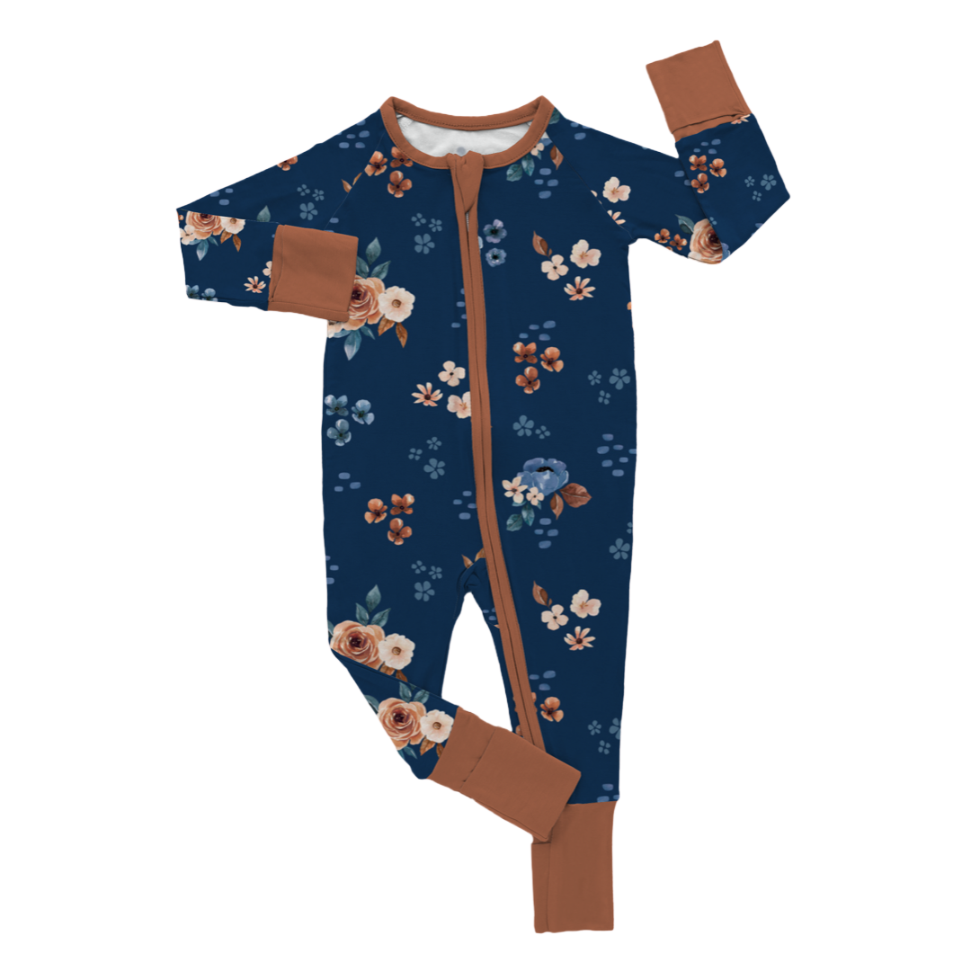 A navy blue baby onesie with a floral pattern and brown trim, laid flat on a white background.