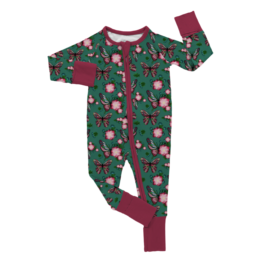 A pair of green pajamas with a floral and butterfly print, featuring pink blossoms and butterflies against a green background, with contrasting burgundy trim.