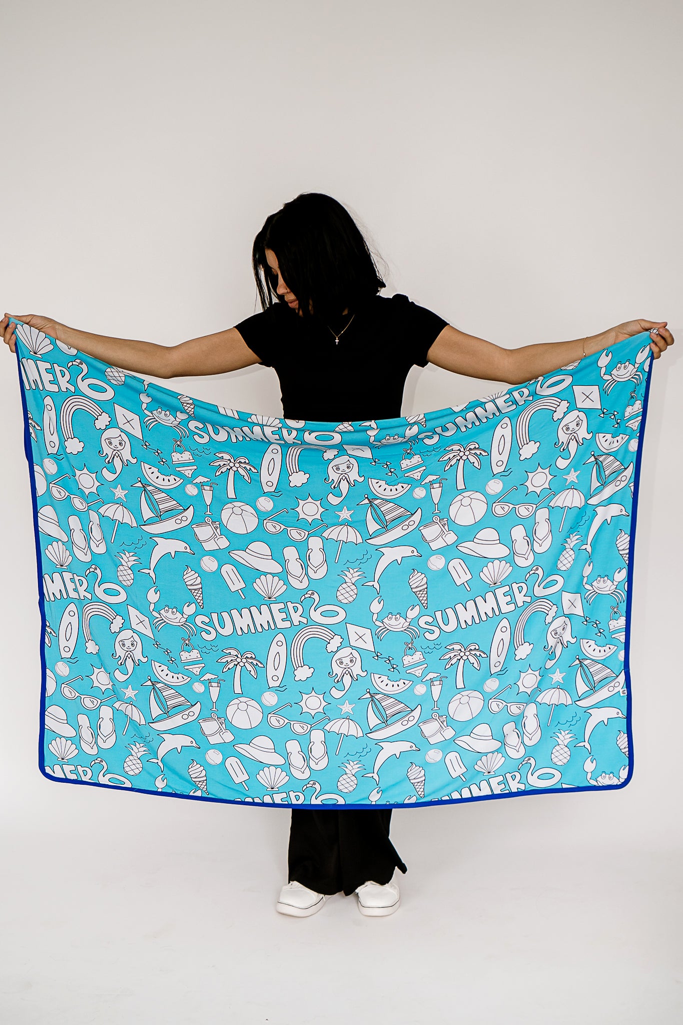 a woman looking down while holding a bamboo blanket featuring our Coastal Cuties print