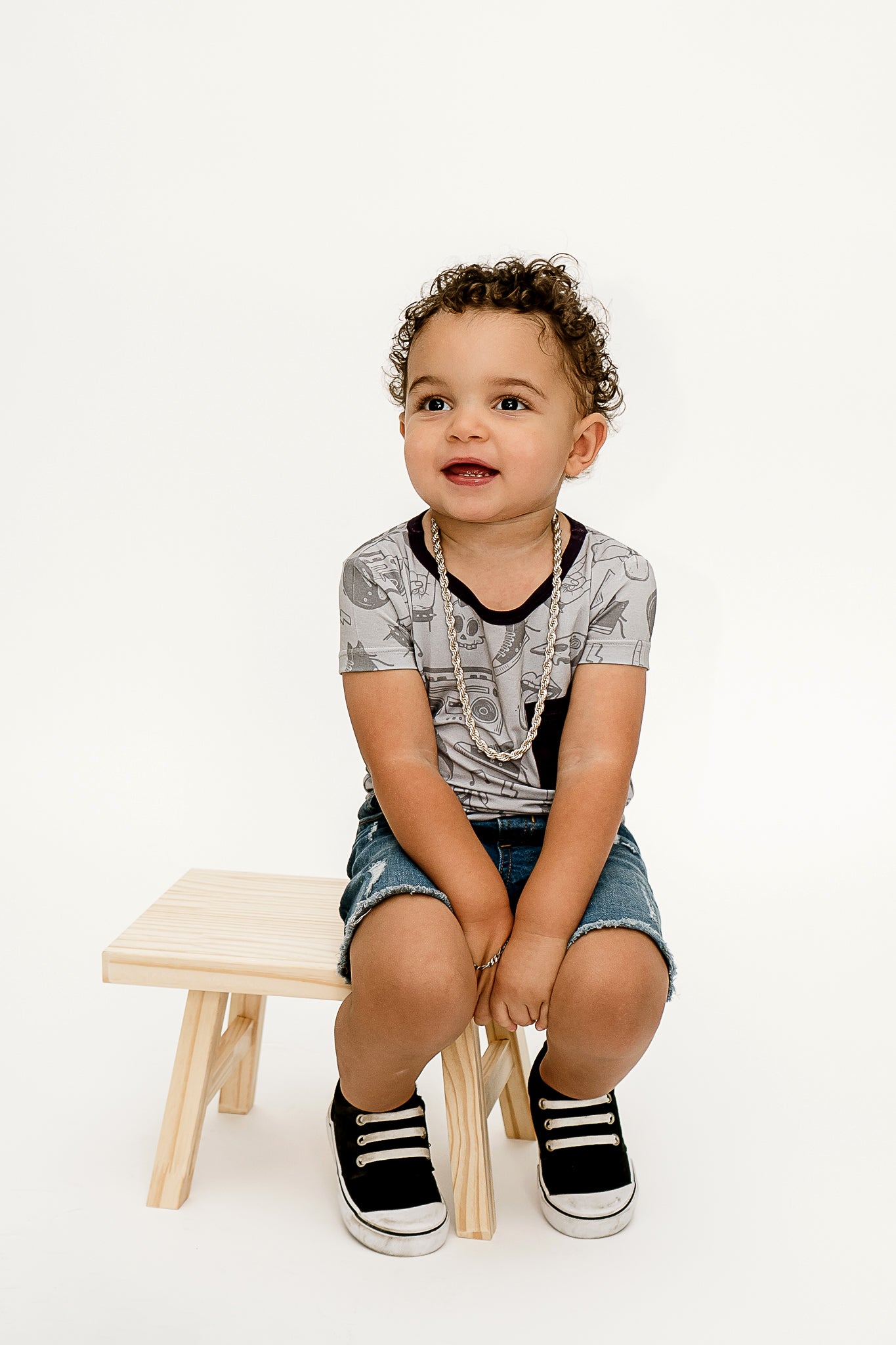 a little boy sitting on a wooden bench wearing Tiny Rebel bamboo shirt
