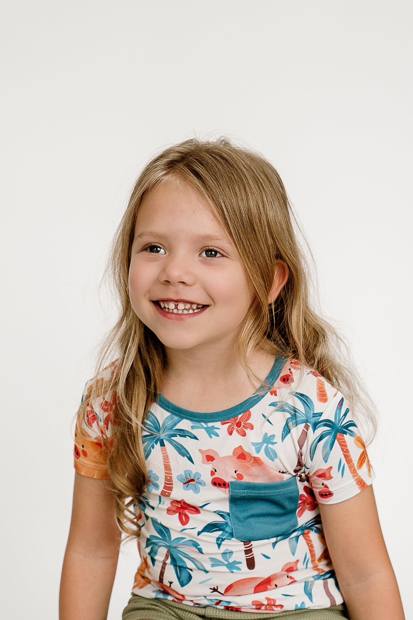 a girl smiling and sitting on a chair wearing Pigs In Paradise bamboo shirt
