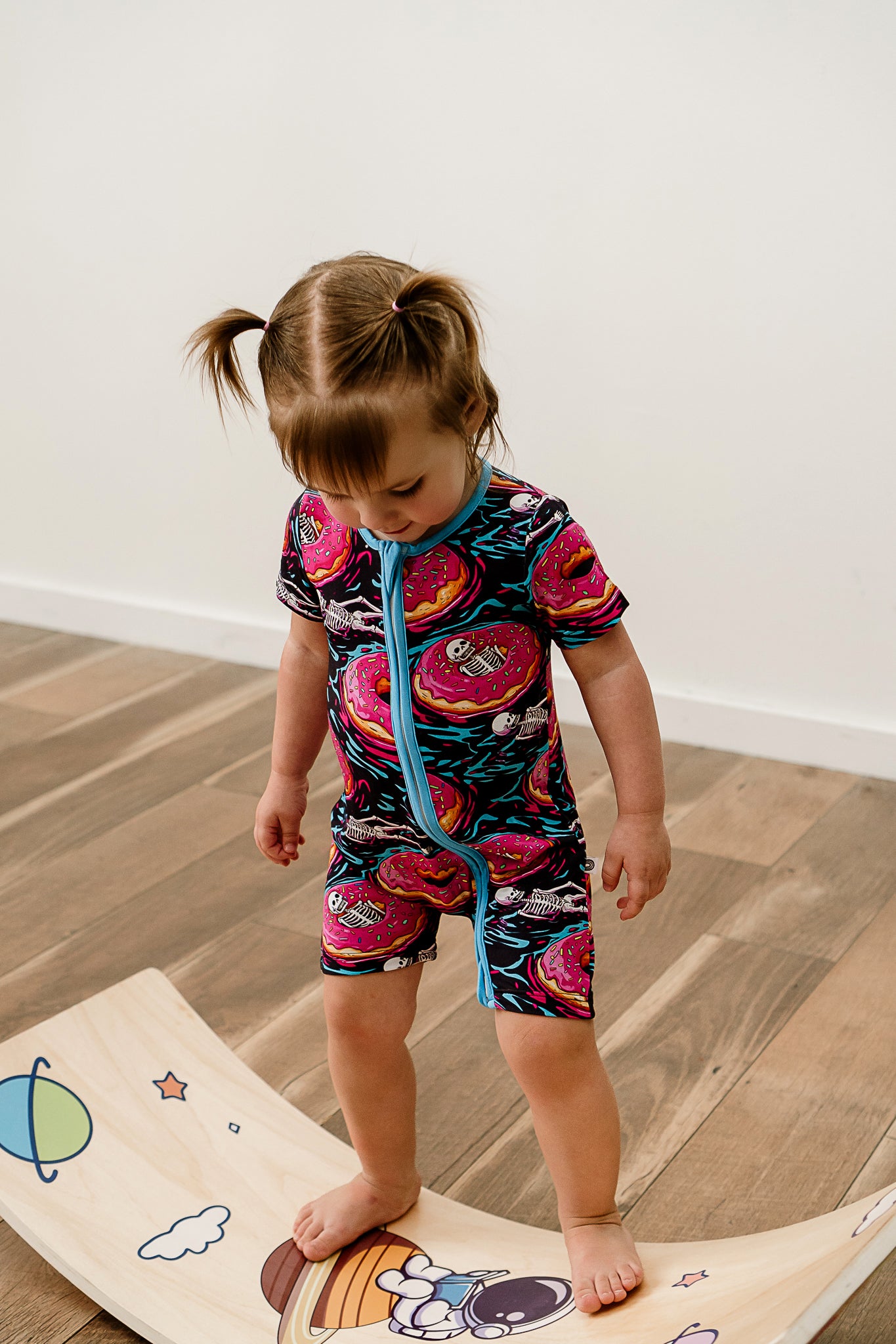 a girl balancing on a balance board and looking down while wearing ghoulish glaze bamboo short sleeved zippy with two way zipper