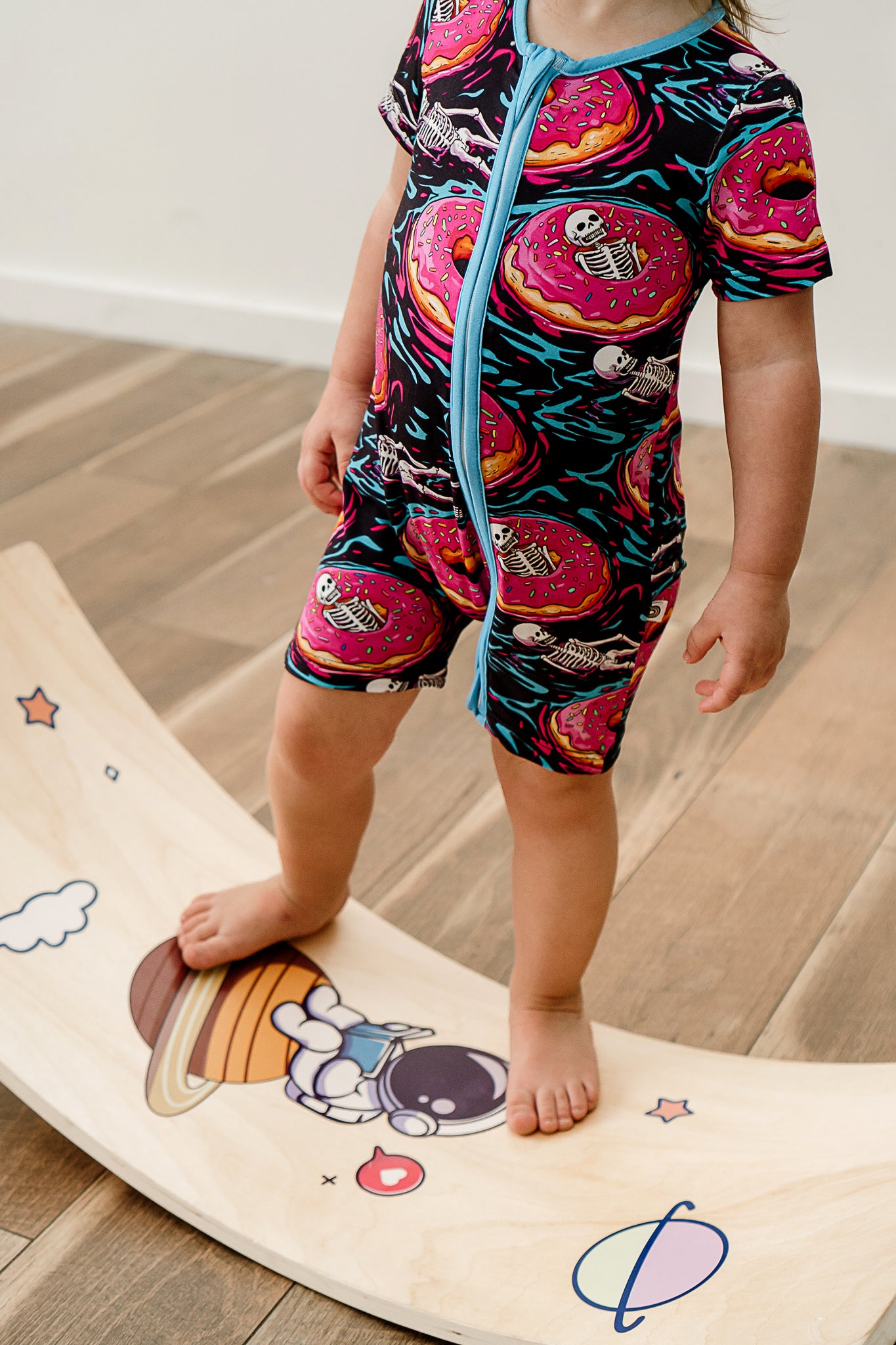 a child standing on a balance board while wearing Ghoulish Glaze bamboo short sleeved zippy