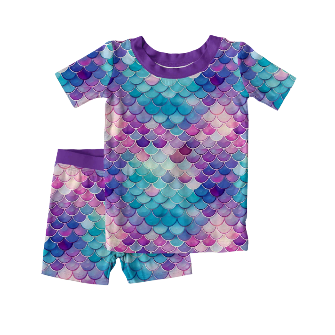 Bamboo children’s 2-piece pajama set with short sleeves and shorts featuring a purple mermaid scale print, shown on a white background.