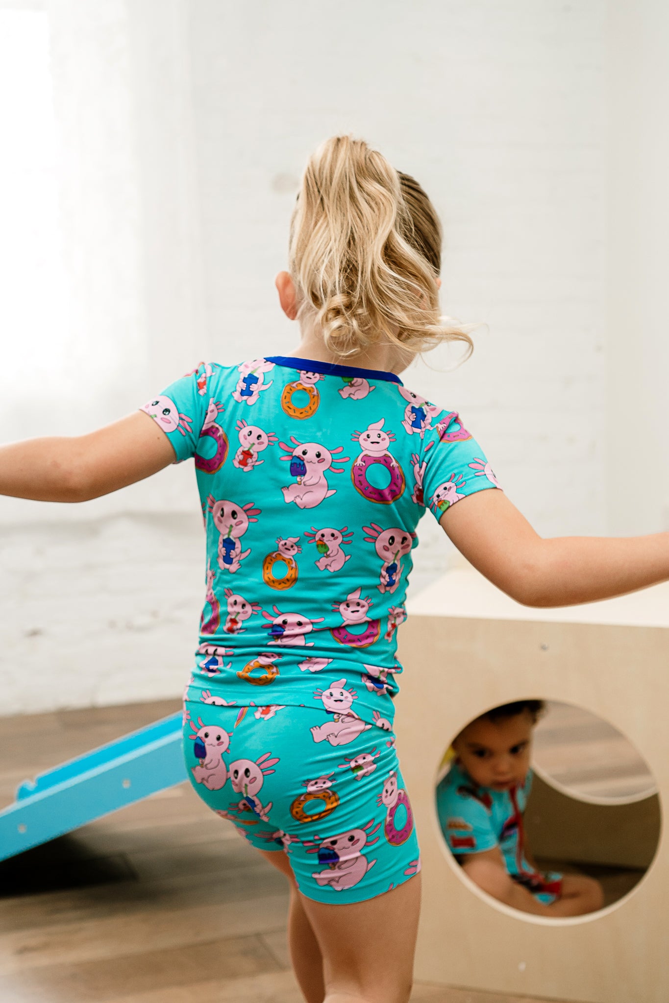 Child twirling joyfully in Axolotlicious bamboo short sleeve and shorts pajamas featuring colorful axolotls.