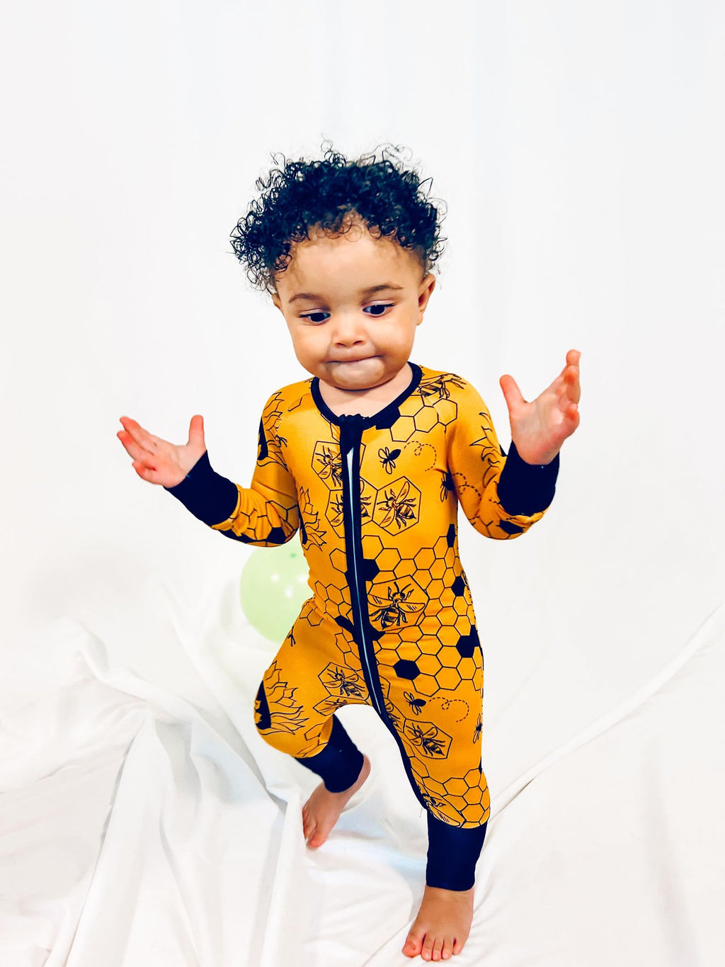 a boy walking while wearing our busy bee print pajama zippy featuring bees and honeycomb on a yellow and black print