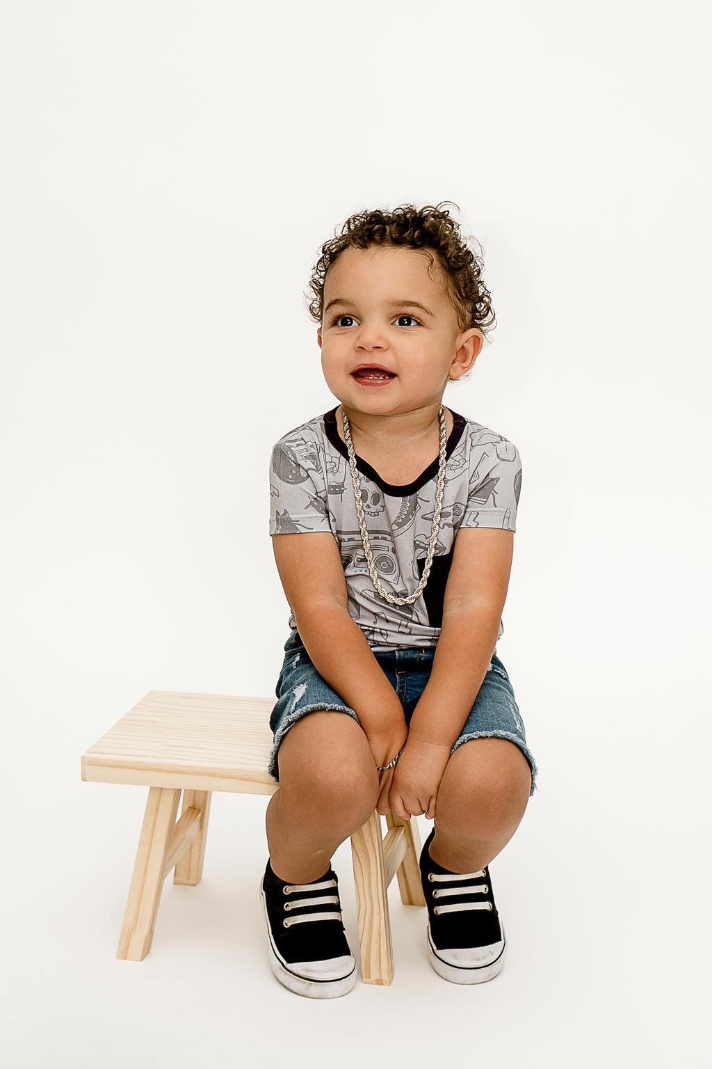 a little boy sitting on a wooden bench wearing Tiny Rebel bamboo shirt