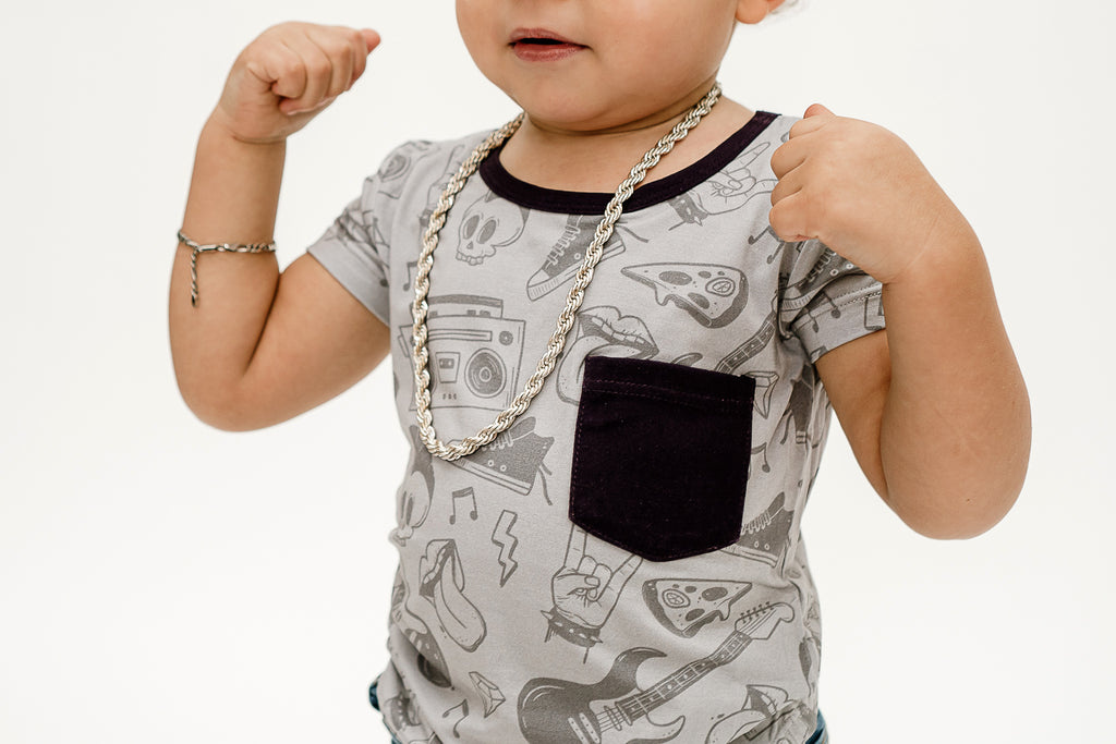 a boy making muscles wearing our Tiny Rebel bamboo shirt with a black pocket