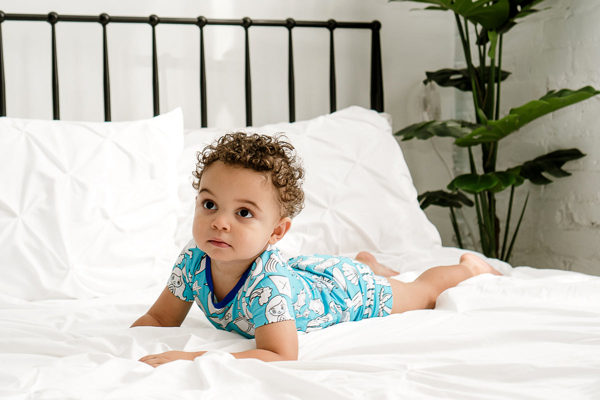 a boy wearing a bamboo pajama set laying on a bed