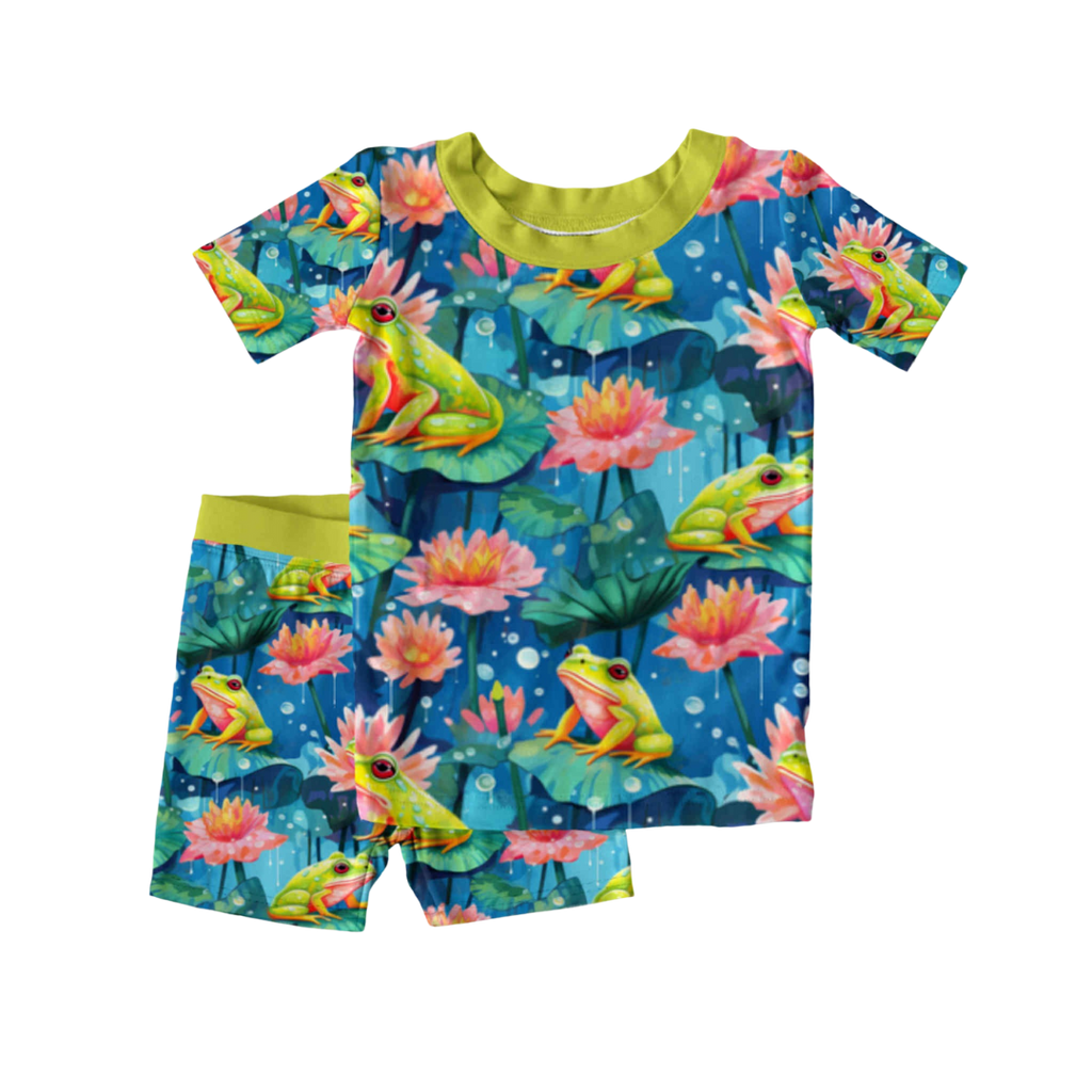 Kids bamboo 2-piece pajama set with a frog and lily pad print called Frog-et Me Not, featuring short sleeves and shorts with green trim, laid flat on white background.