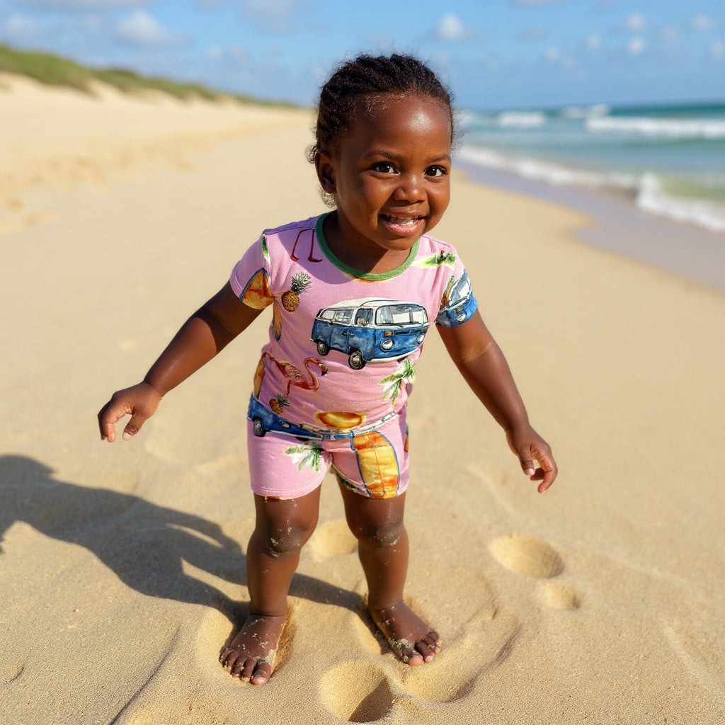 little girl wearing surfing bamboo pajamas and laughing in the sand. 
