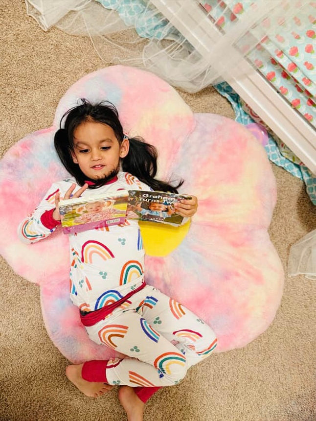 Girl reading a book while laying on the floor in Mama’s Little Rainbow bamboo pajamas—comfortable, breathable kids sleepwear perfect for quiet moments.