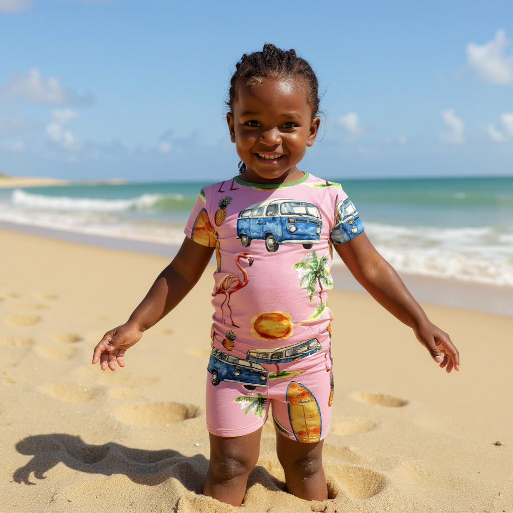 Young girl wearing tropical surfing pajamas with half her legs in the sand. 