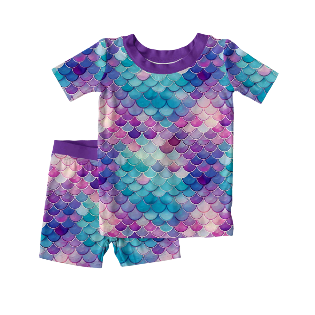 Bamboo children’s 2-piece pajama set with short sleeves and shorts featuring a purple mermaid scale print, shown on a white background.