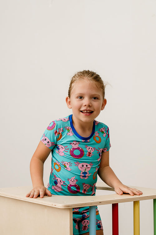 Little girl climbing blocks on the floor in Axolotlicious bamboo pajamas with playful axolotl print.