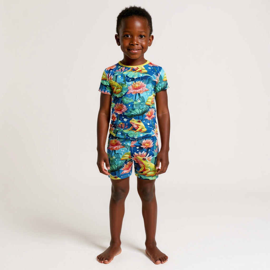 Young boy wear frog pajamas standing in a white room